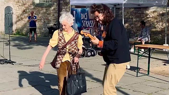 Older lady gets down and groovy with street musician